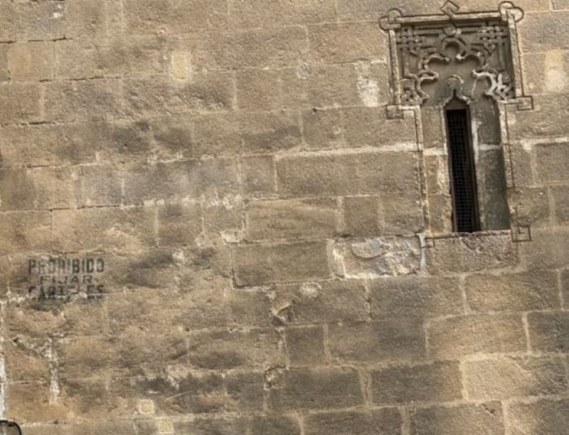 Inscripción histórica pintada en el muro de piedra de la Torre de la Atalaya en Jerez que advierte la prohibición de fijar carteles.