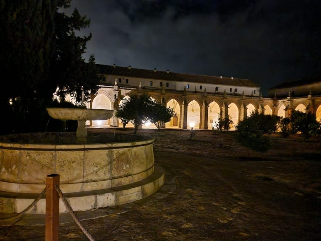 Fuente central y claustro del Monasterio de la Cartuja de Jerez iluminados suavemente durante la noche.