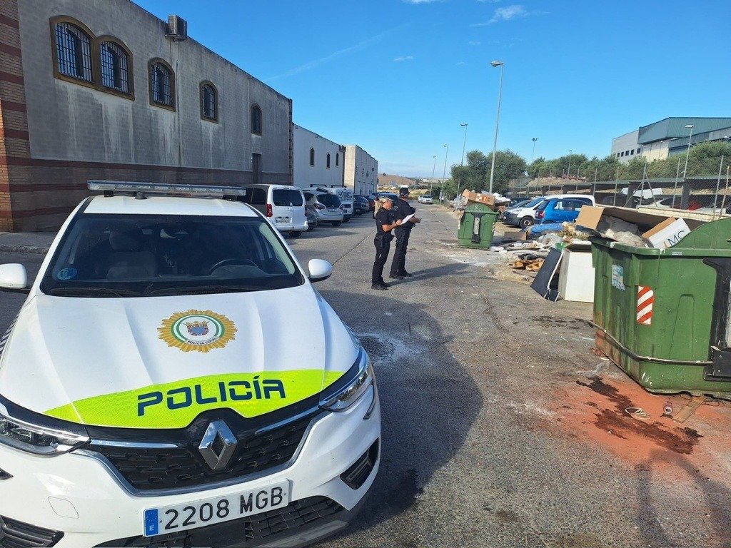 Agentes de la Policía Local realizan labores de vigilancia y control contra el vertido irregular de residuos junto a contenedores en una zona industrial.
