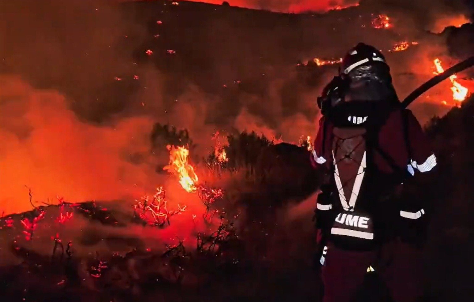 Efectivo de la UME trabajando en la extinción de un grave incendio forestal durante la noche.
