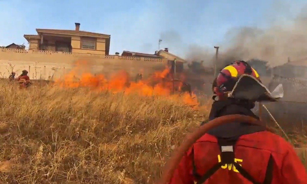 Efectivo de la UME combatiendo un incendio de interfaz urbana que se aproxima a viviendas en una zona residencial.