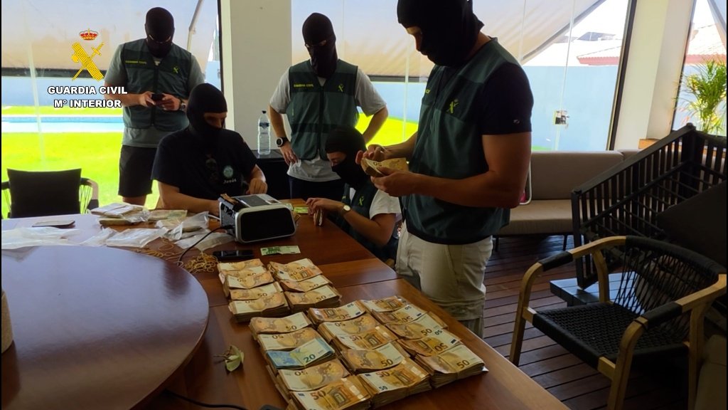 Agentes de la Guardia Civil encapuchados contando fajos de billetes incautados sobre una mesa durante la operación Sorela contra el blanqueo de capitales.