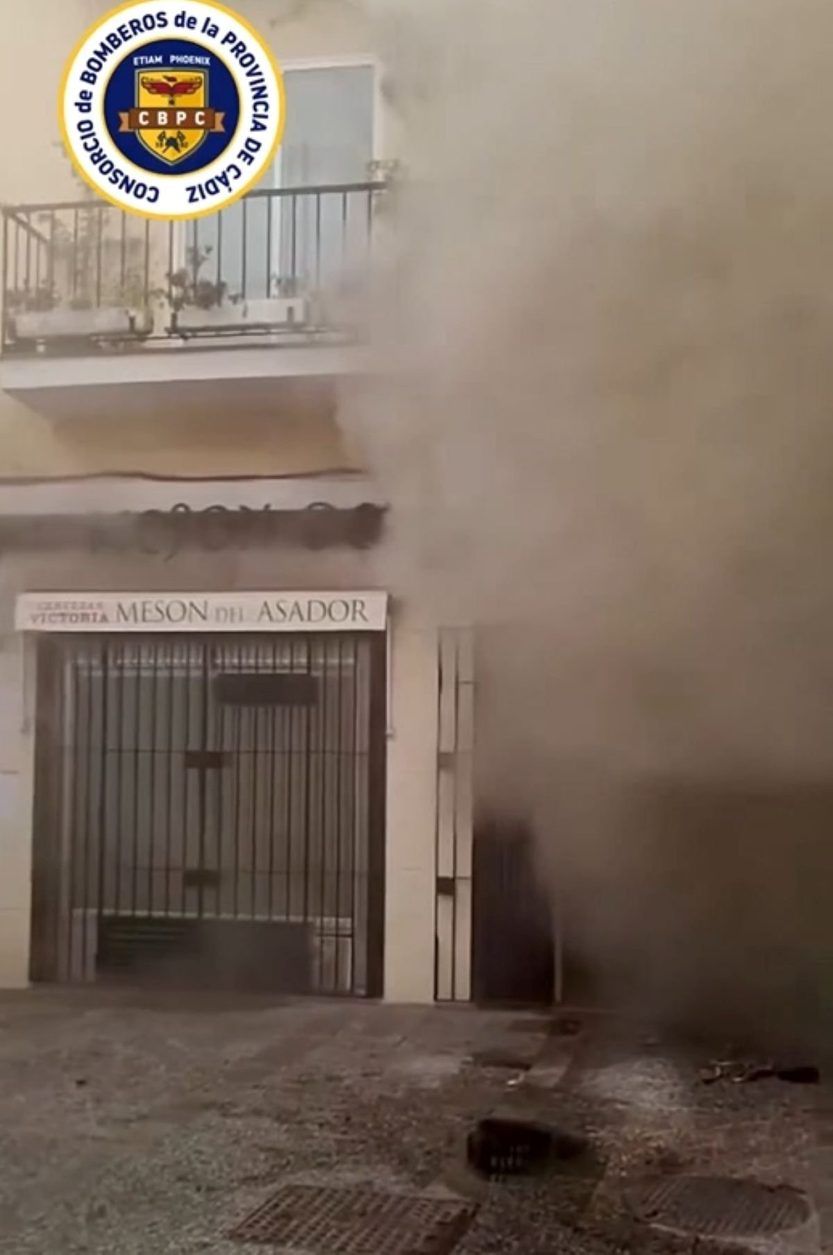 Humo saliendo de la fachada de un restaurante en la calle Remedios de Jerez durante un incendio atendido por bomberos.