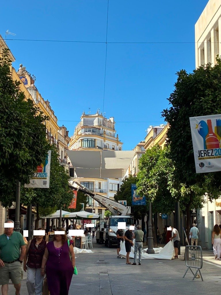 Operarios municipales utilizando un camión grúa para el despliegue de las lonas de los toldos en calle Larga de Jerez.