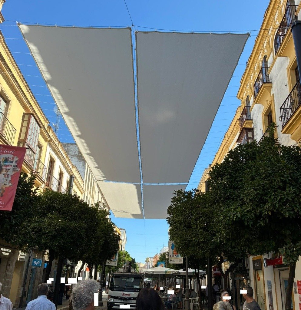 Instalación de toldos blancos sobre la calle Larga de Jerez para proteger del sol durante el verano.