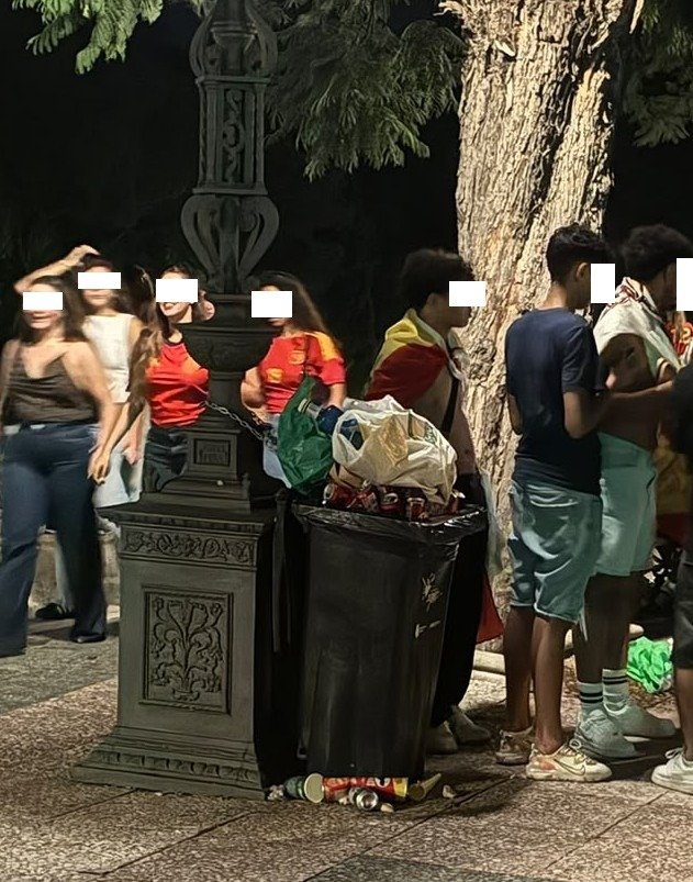 Papelera desbordada de residuos junto a jóvenes celebrando el evento en la Alameda Vieja de Jerez.