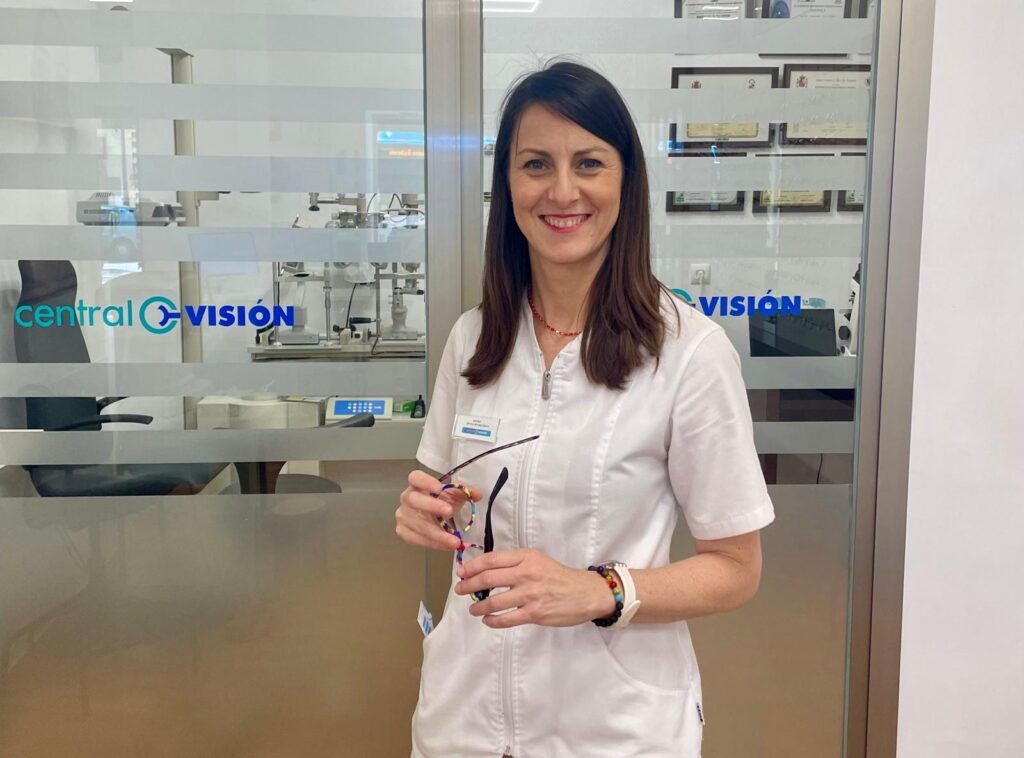 Sandra Ríos Rubio, propietaria de la óptica Central Visión en Jerez, sonriendo en su lugar de trabajo con unas gafas en la mano.