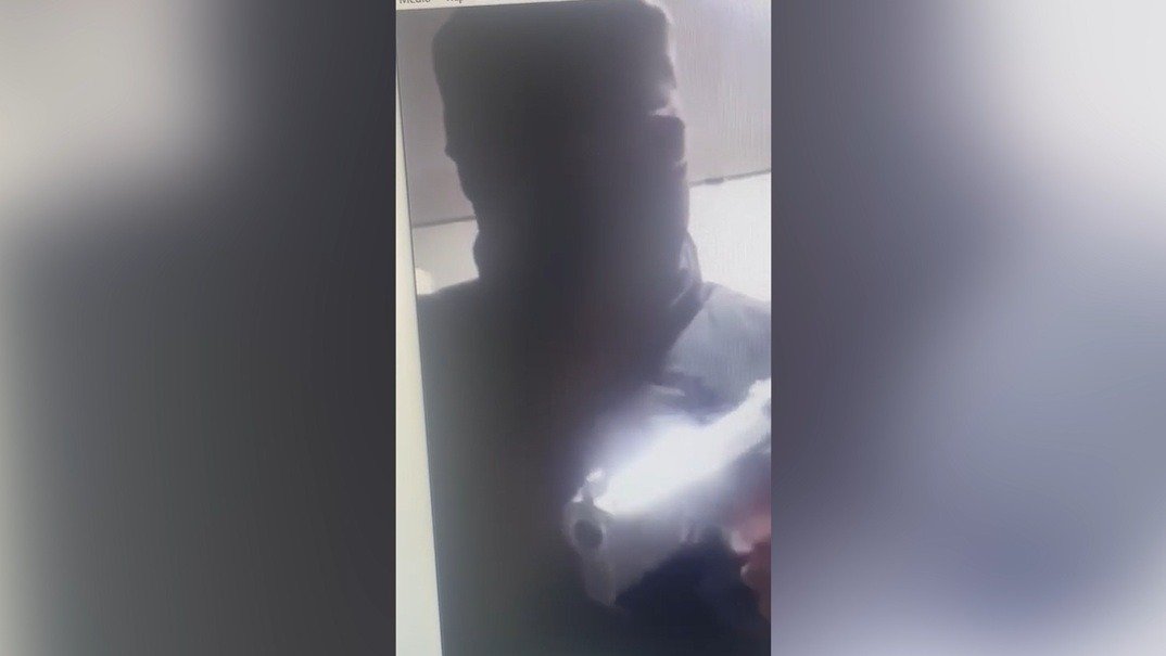Persona con el rostro cubierto y un arma de fuego utilizada para intimidar a las víctimas de sextorsión.