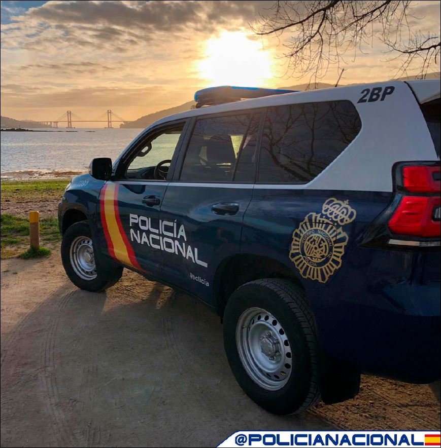 Vehículo oficial de la Policía Nacional estacionado junto a la costa durante un atardecer.