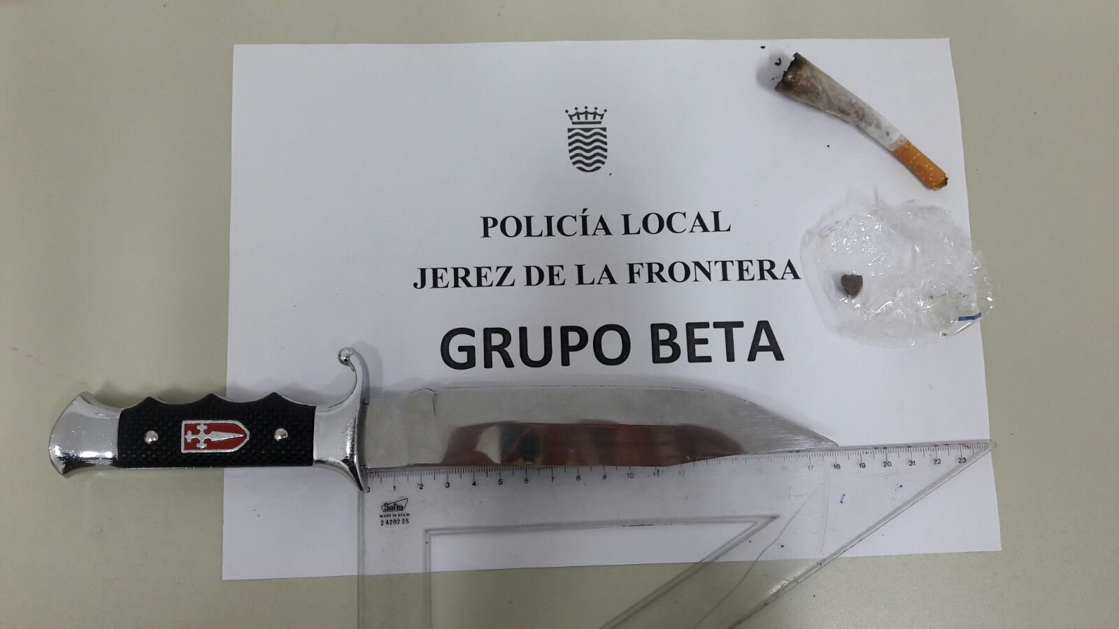 Arma blanca de grandes dimensiones de hoja metálica y mango decorado, junto a un porro consumido y una pequeña bolsa con hachís, requisados por el Grupo Beta de la Policía Local de Jerez de la Frontera.