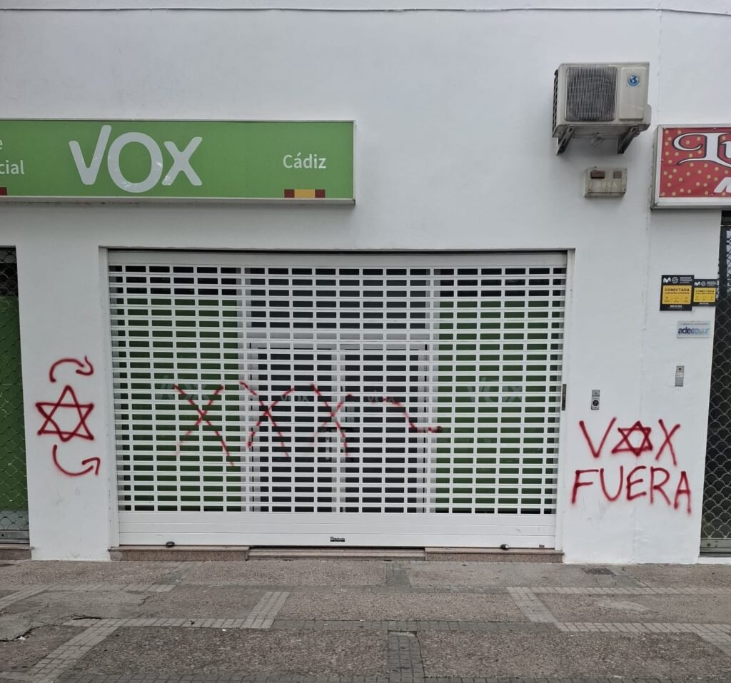 Fachada de la sede de Vox en Jerez vandalizada con pintadas rojas y mensajes en la persiana y paredes.