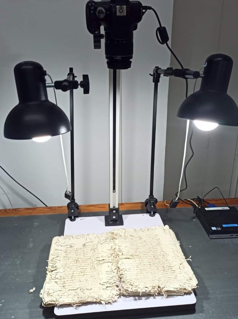 Proceso de digitalización de un protocolo notarial antiguo con cámara réflex y focos de iluminación