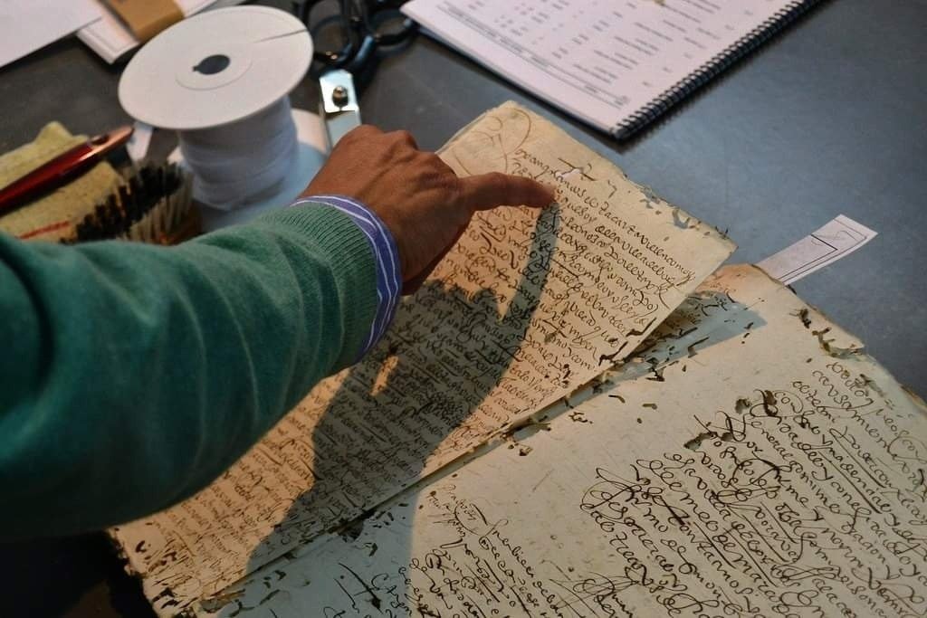 Investigador analizando un libro de protocolos notariales antiguos en el archivo documental
