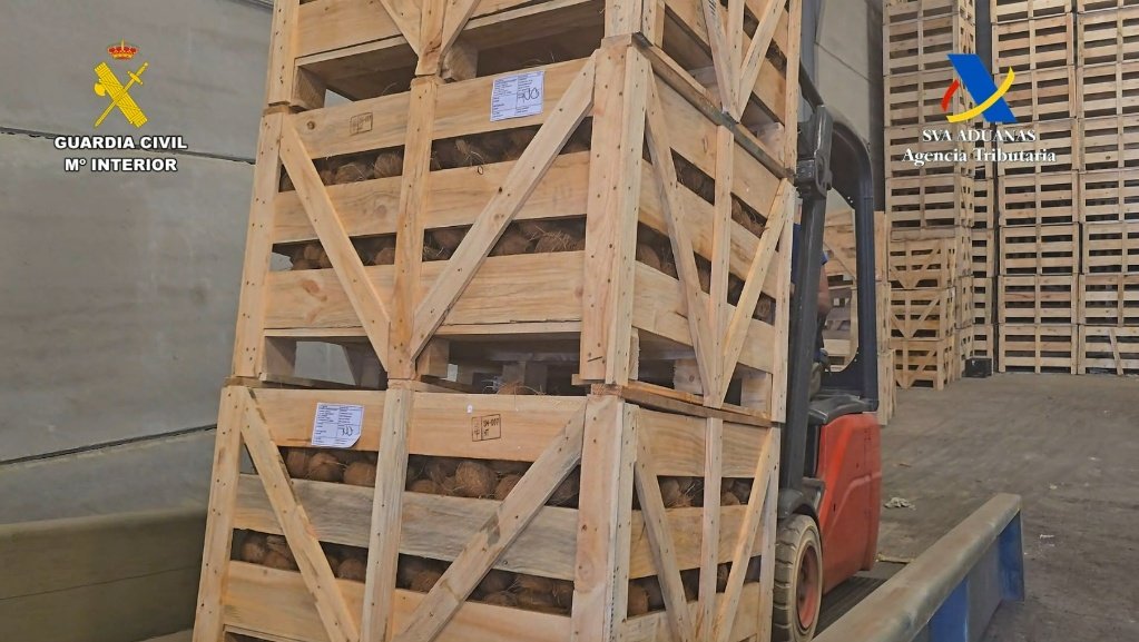 Carretilla elevadora trasladando grandes cajas de madera apiladas con cocos en el interior de una nave industrial durante el operativo policial.