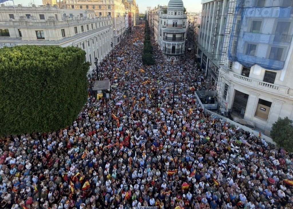 Vista panorámica de la avenida de la Constitución de Sevilla repleta de personas ondeando banderas en apoyo a Ceuta.