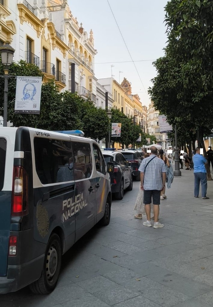 Transeúntes observando el dispositivo policial y las patrullas de la Policía Nacional estacionadas en la concurrida Calle Larga de Jerez.