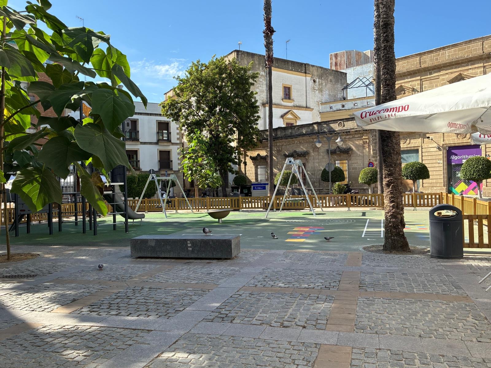Parque infantil en la Plaza del Progreso de Jerez adyacente a terrazas de hostelería.