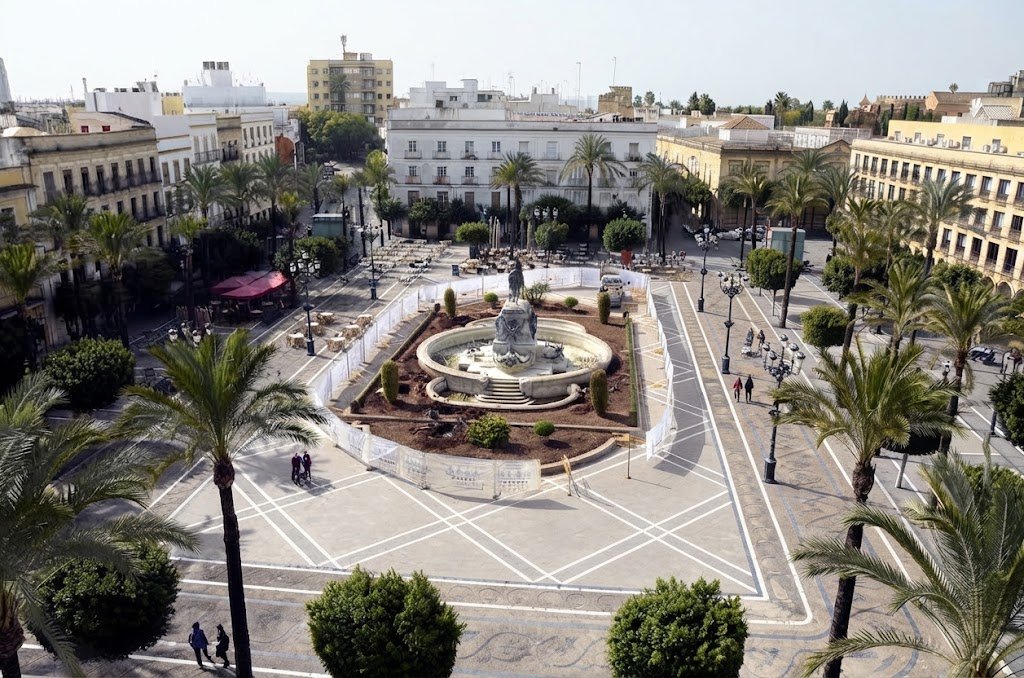 Fotografía aérea actual de alta definición de la Plaza del Arenal de Jerez de la Frontera, mostrando su configuración peatonal definitiva, el pavimento ajedrezado, las palmeras y el monumento central restaurado.