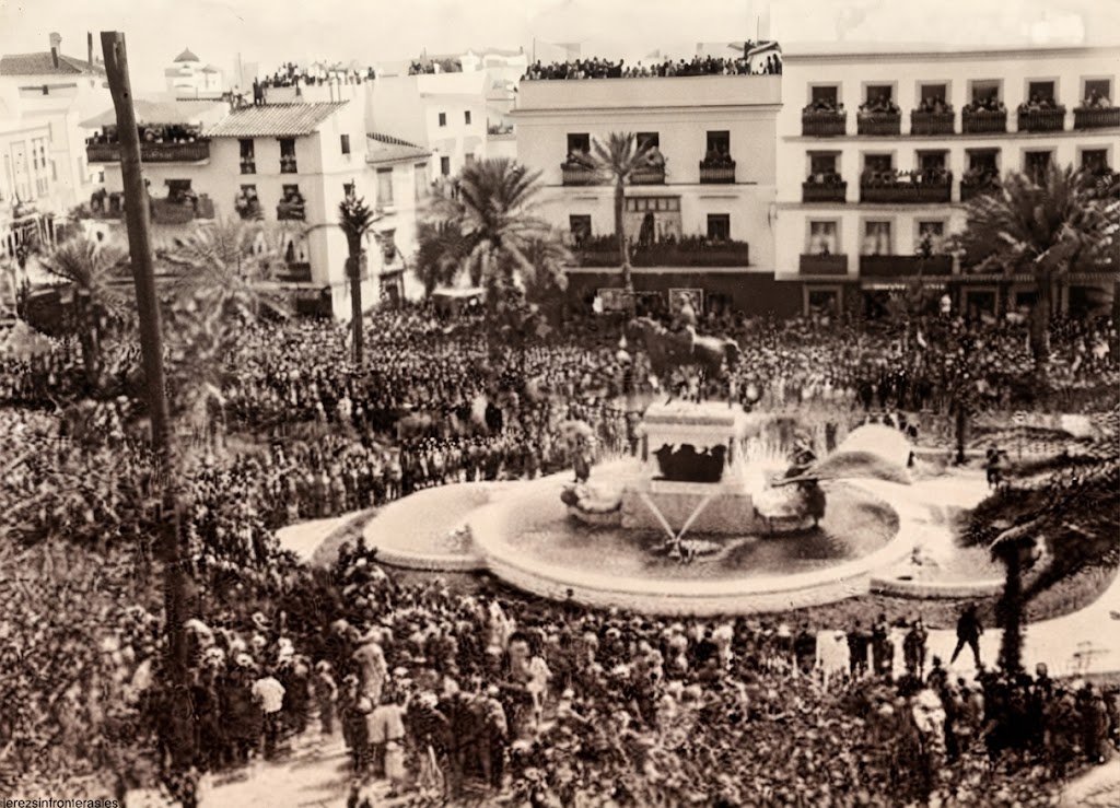 Fotografía histórica de la Plaza del Arenal de Jerez de la Frontera, restaurada digitalmente y mejorada en su calidad y resolución, mostrando una vista aérea de la inauguración del monumento ecuestre con una multitud densa y las fuentes activas en la década de 1920.