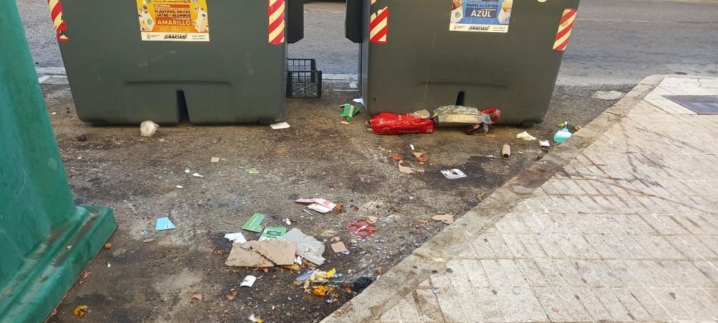 Suelo sucio y con restos de basura dispersos en los aledaños de los contenedores del Parque Atlántico tras la recogida parcial, evidenciando la falta de barrido y baldeo[cite: 14].