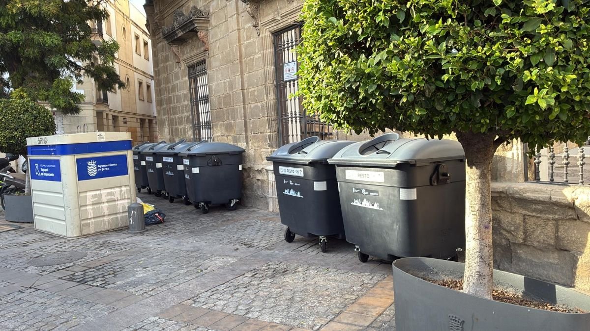 Fila de contenedores grises de basura y módulo de recogida situados de forma permanente en la Plaza del Progreso de Jerez de la Frontera.