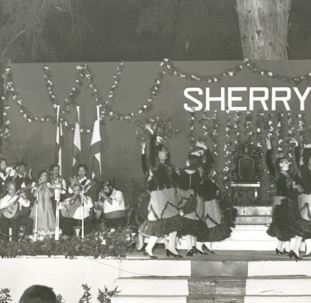 Cuadro flamenco y grupo de guitarras en un escenario decorado bajo el rótulo Sherry durante la Feria de Jerez a finales de los años 70.