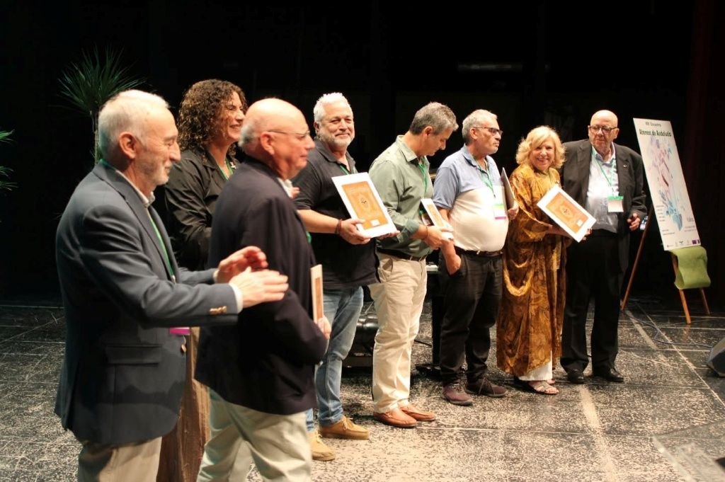 Varios representantes y galardonados en el escenario durante el encuentro anual de la Federación de Ateneos de Andalucía en Cabra, sosteniendo diplomas y reconocimientos.