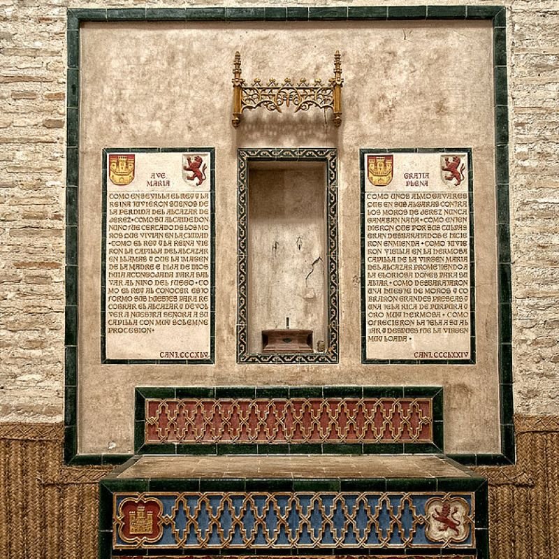 Lápidas cerámicas conmemorativas de la conquista castellana de Jerez en la capilla del Alcázar de Jerez de la Frontera, flanqueando un hornacina central.