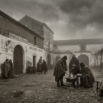 Recreación histórica en tono sepia de un patio de bodegas en Jerez de la Frontera durante el año sin verano de 1816, con personas abrigadas con mantas y capas junto a una hoguera bajo un cielo oscuro y plomizo a las cuatro de la tarde.